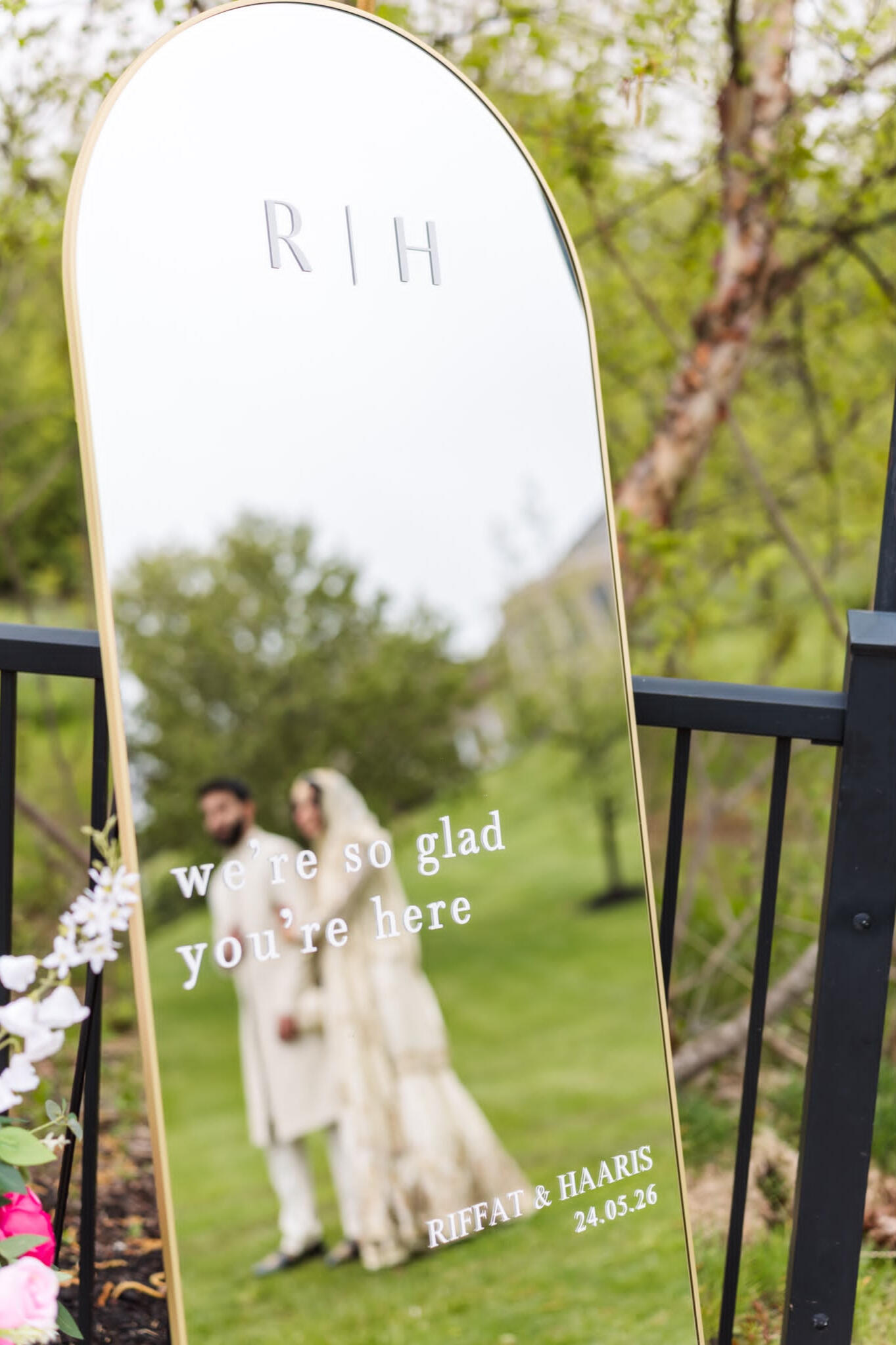 Welcome Wedding Mirror in Oakville “Outdoor wedding welcome mirror in Caledon, Ontario, reading ‘We’re so glad you’re here,’ with the couple reflected in the glass.”